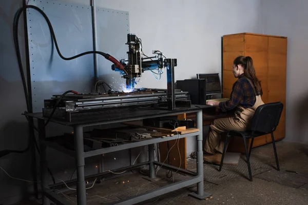 Saldatore che utilizza computer vicino alla saldatrice in fabbrica — Foto stock