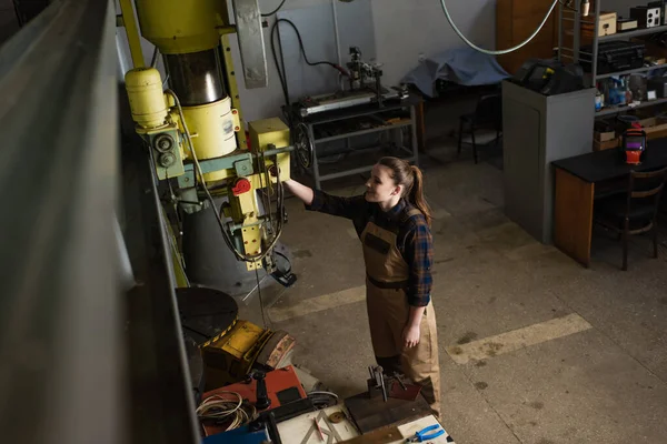 Vue grand angle du soudeur souriant travaillant avec une machine à souder en usine — Photo de stock