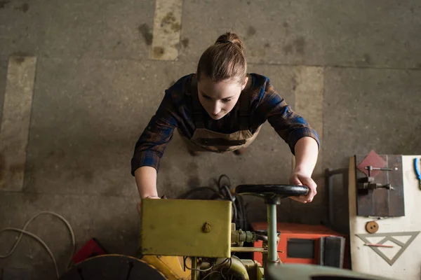 Overhead view of welder in shirt and overalls working on welding machine in factory — Stockfoto