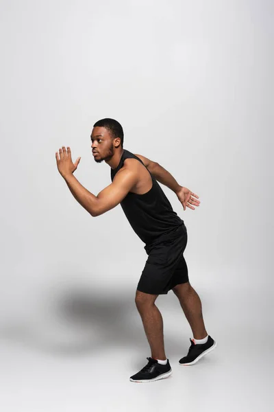 Full length of african american sportsman running fast on grey — Stock Photo