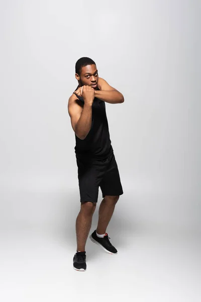 Повна довжина афроамериканського спортсмена, що розігрівається на сірому — стокове фото