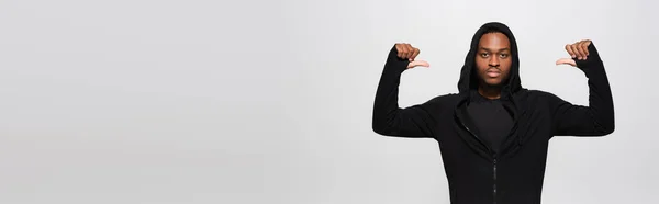 Молодий афроамериканський чоловік в светрі вказує пальцями на себе ізольований на сірому, банер — стокове фото