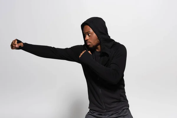 African american man in hoodie fighting on grey — Stockfoto