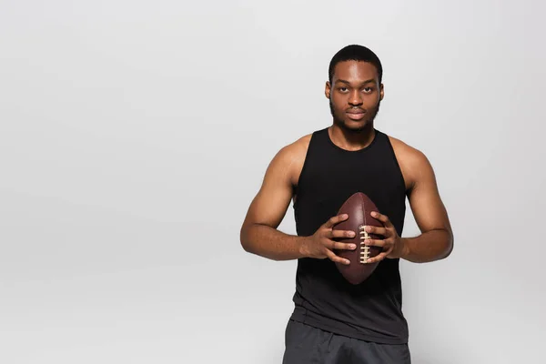 Starker afrikanisch-amerikanischer Sportler hält Rugbyball isoliert auf grau — Stockfoto