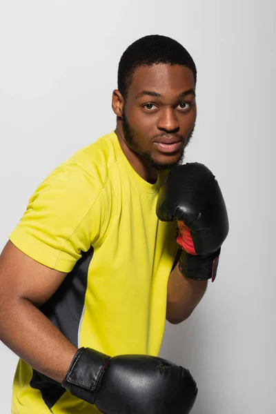Strong african american sportsman working out in boxing gloves isolated on grey — Stock Photo