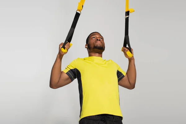 Сильный африканский американский спортсмен, тренирующийся с полосами сопротивления изолированными на сером — стоковое фото