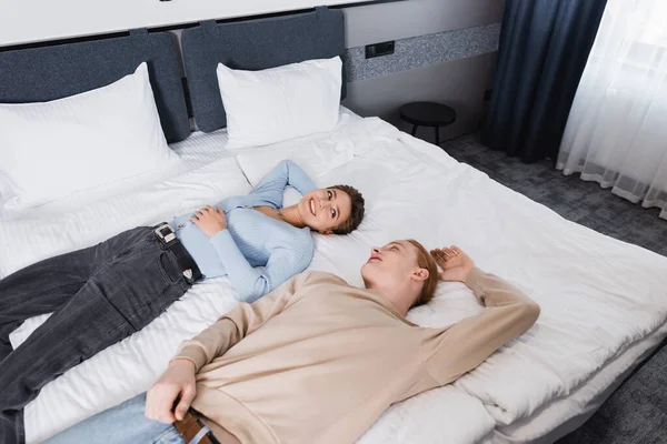 Високий кут зору усміхненої пари лежить на ліжку в готельному номері — стокове фото
