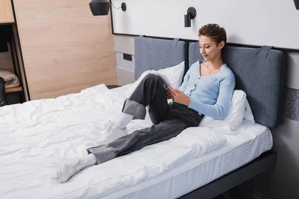 Молода жінка використовує цифровий планшет на ліжку в готельному номері — стокове фото