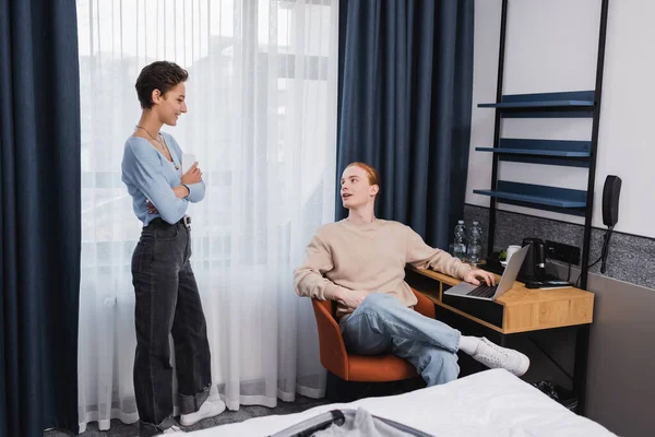 Couple positif utilisant des appareils dans la chambre d'hôtel moderne — Photo de stock