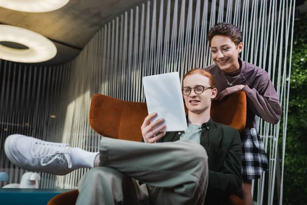 Pareja sonriente usando tableta digital en el vestíbulo del hotel - foto de stock