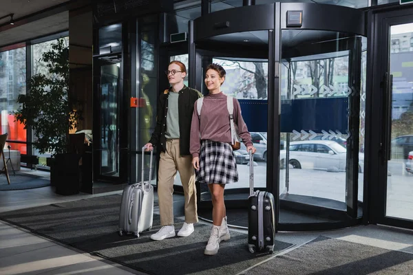 Junges Paar mit Koffern läuft in Hotellobby — Stockfoto