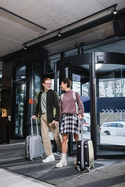 Young coupe with suitcases looking at each other in hotel lobby — Stock Photo