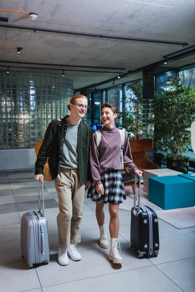 Positive couple with baggage walking in hotel lobby — Stockfoto