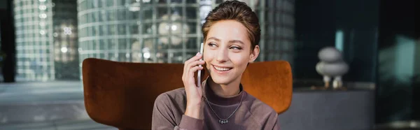 Молодая женщина разговаривает по мобильному телефону в вестибюле отеля, баннер — стоковое фото