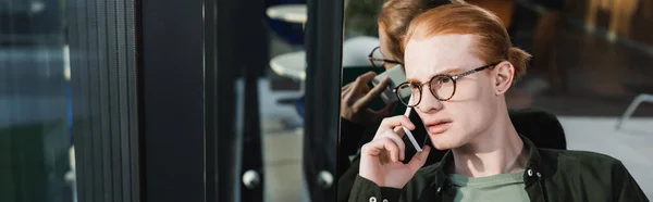 Giovane con gli occhiali che parla al cellulare in hotel, striscione — Foto stock