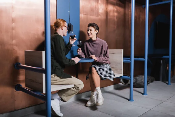 Happy young woman holding glass of wine near boyfriend in hotel — стоковое фото