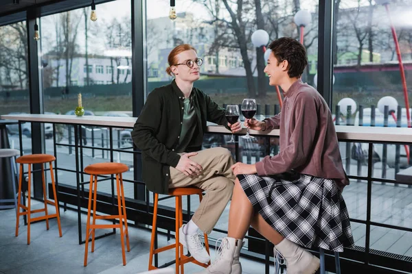 Pareja positiva de viajeros sosteniendo copas de vino en el hotel - foto de stock