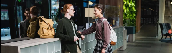 Side view of tourists with backpacks talking near hotel reception, banner — Stock Photo