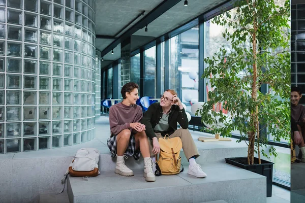 Young travelers with backpacks sitting on stairs in hotel — Stockfoto