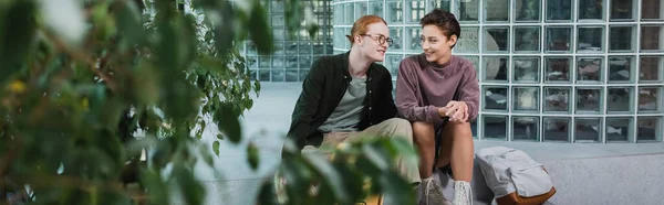 Young tourists talking near backpack and plants in hotel, banner — Stock Photo