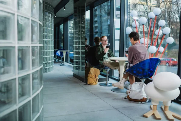 Jeune couple tenant du vin près des sacs à dos dans le café de l'hôtel — Photo de stock