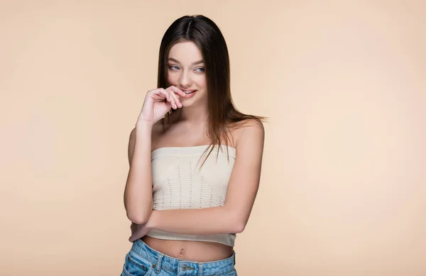 Pretty young woman in crop top with bare shoulders smiling isolated on beige — стоковое фото