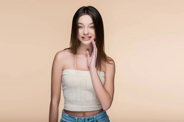 Happy young woman in crop top with bare shoulders isolated on beige — Stock Photo