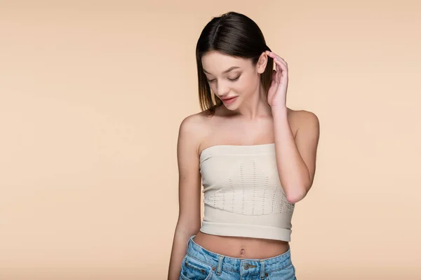 Young and shy woman in crop top with bare shoulders isolated on beige — Stock Photo