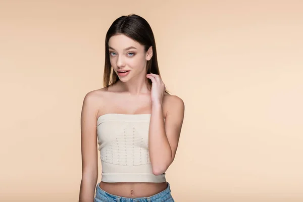 Young woman in crop top with bare shoulders posing isolated on beige — Stock Photo