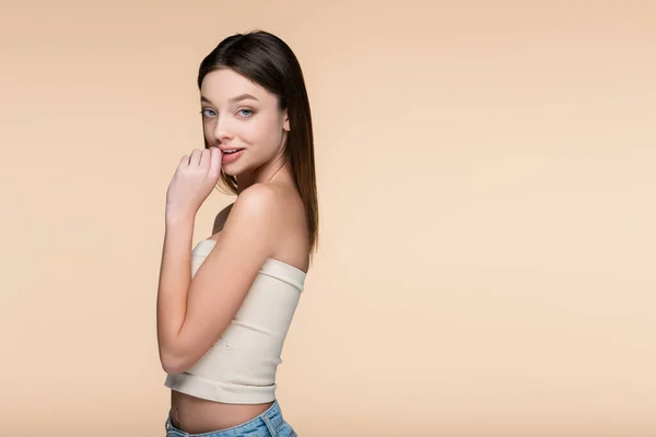 Joyful young woman in crop top with bare shoulders isolated on beige — стоковое фото