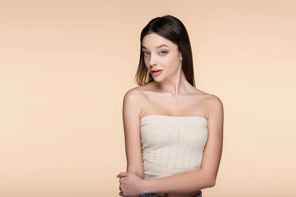 Young brunette woman in crop top with bare shoulders isolated on beige — Fotografia de Stock