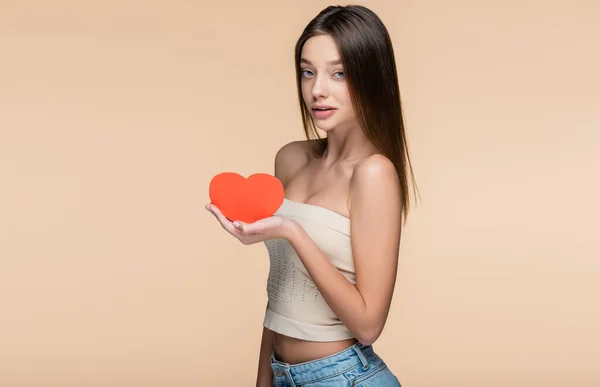 Woman in crop top holding red paper cut heart isolated on beige — Stockfoto