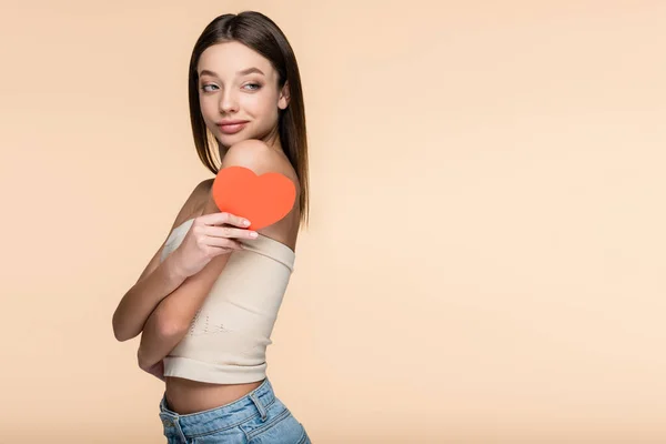 Joyful woman in crop top holding red paper heart isolated on beige — Stockfoto