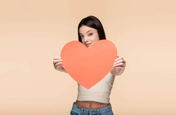 Blurred and joyful woman holding red paper heart isolated on beige — Stockfoto