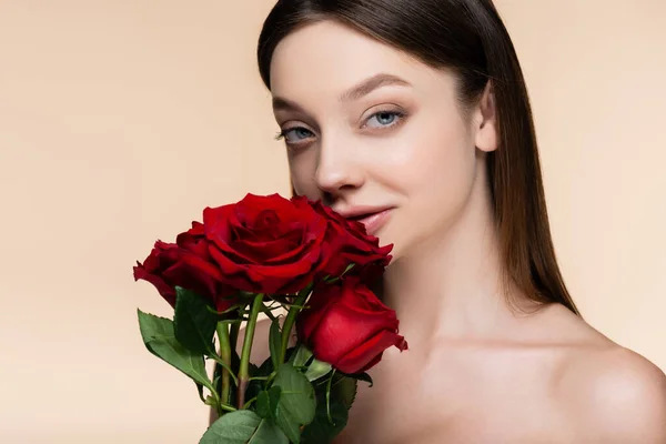 Young woman near bouquet of red roses isolated on beige — Stockfoto