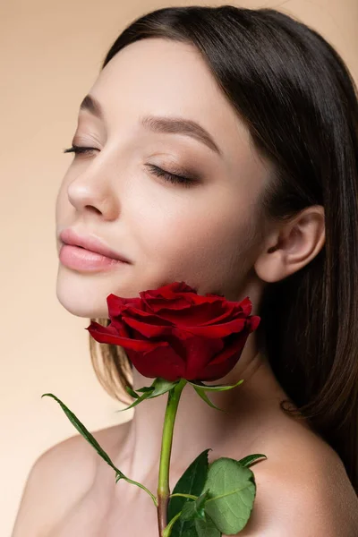 Молода жінка з закритими очима біля троянди ізольована на бежевому — стокове фото