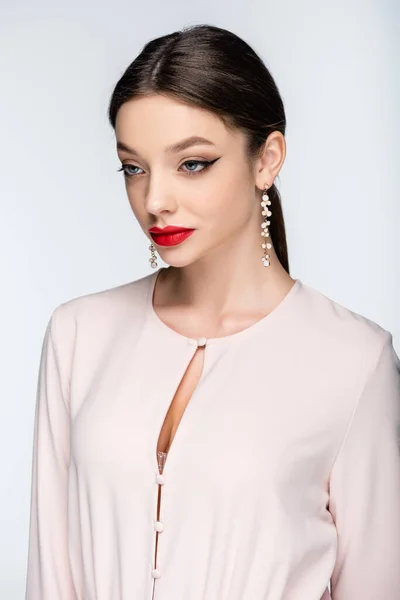 Pretty woman in earrings and blouse looking away while posing isolated on grey — Stock Photo