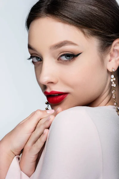 Bonita mujer en pendientes y maquillaje brillante aislado en gris - foto de stock