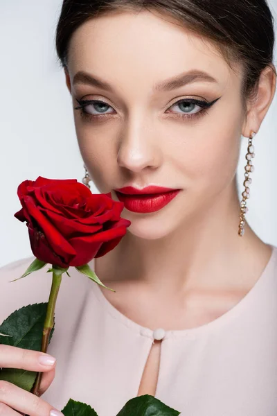 Pretty woman in earrings holding red rose isolated on grey — Fotografia de Stock