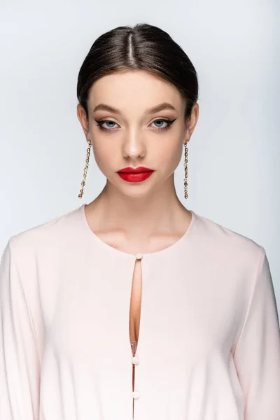 Brunette woman in earrings and blouse looking at camera isolated on gray — Stock Photo