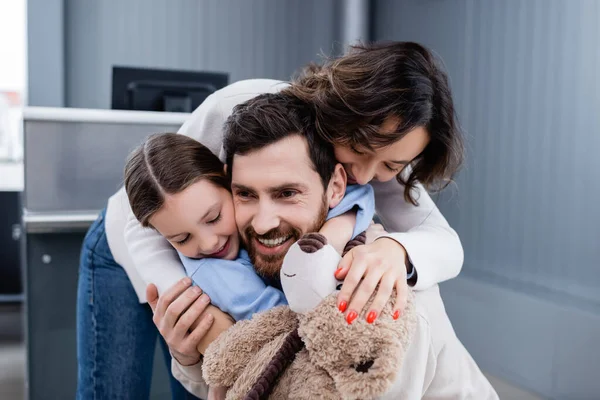 Happy woman and kid hugging bearded man in airport — стоковое фото