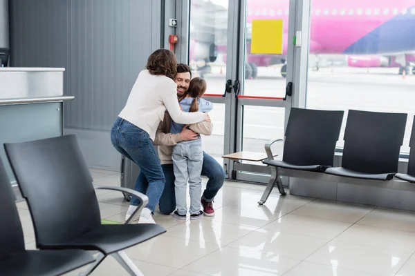 Fröhlicher Mann umarmt Familie am Flughafen — Stockfoto