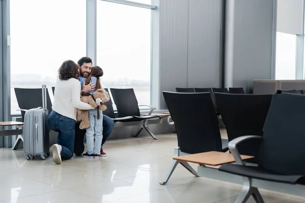 Amorosa y feliz familia abrazo en aeropuerto salón - foto de stock