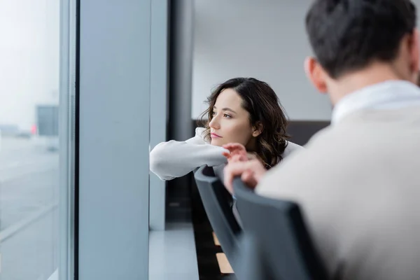 Pensive woman looking at window near blurred husband — Stockfoto