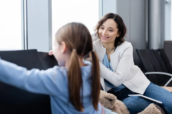 Happy mother looking at blurred daughter in airport lounge — Stock Photo