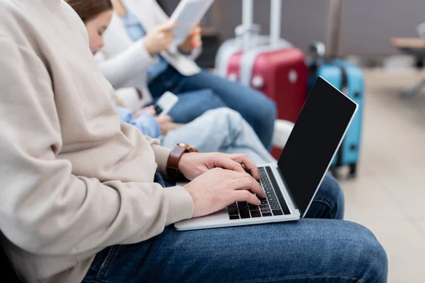 Man using laptop near blurred family in airport - foto de stock