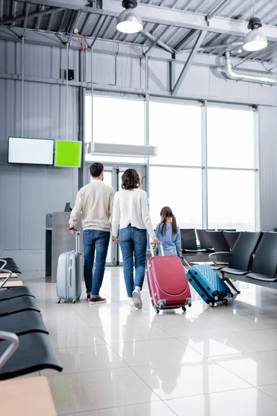 Back view of family standing with luggage in airport hall — стоковое фото