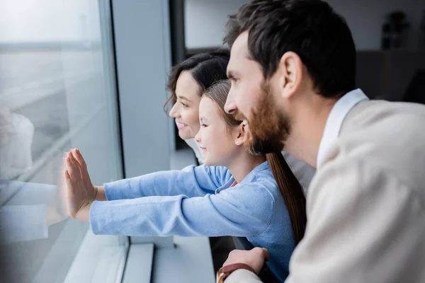 Seitenansicht einer glücklichen Familie beim Blick auf das Fenster im Flughafen — Stockfoto