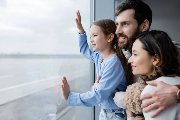 Famille positive regardant fenêtre à l'aéroport — Photo de stock