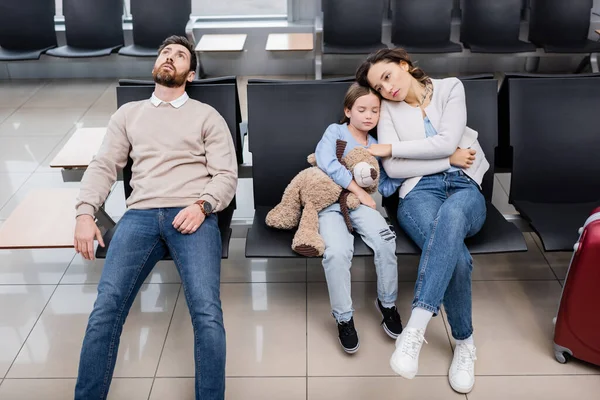 Нудний чоловік чекає з дочкою і дружиною в залі для аеропортів — стокове фото